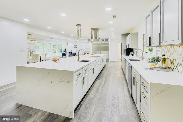 kitchen featuring light hardwood / wood-style flooring, sink, a large island, pendant lighting, and island range hood