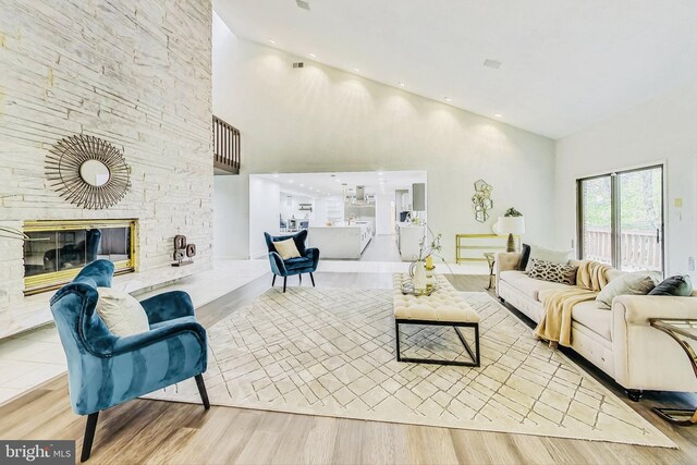 living room with a fireplace, a towering ceiling, and light hardwood / wood-style floors