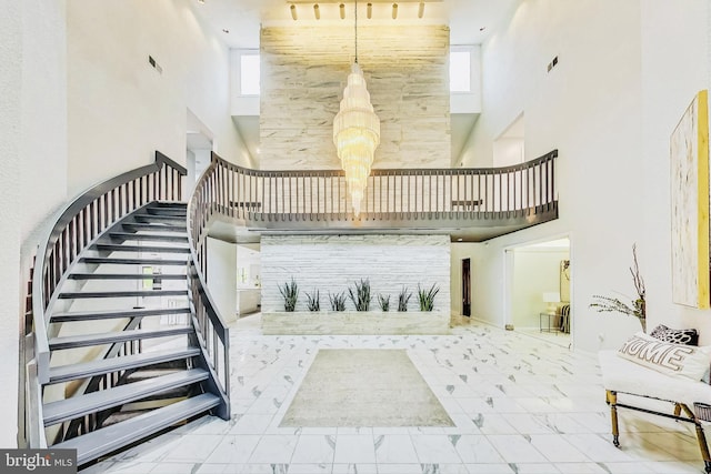 staircase featuring plenty of natural light, marble finish floor, and a towering ceiling