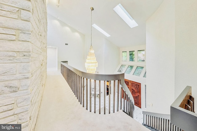 hallway featuring high vaulted ceiling and a skylight