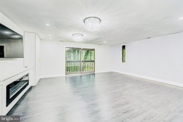 unfurnished living room featuring an inviting chandelier and hardwood / wood-style floors