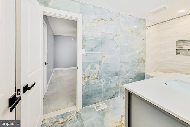 bathroom featuring a tile shower and vanity