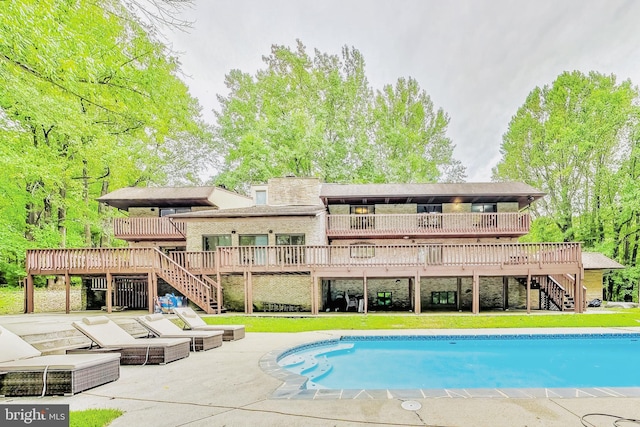 outdoor pool featuring a deck, a lawn, stairs, and a patio