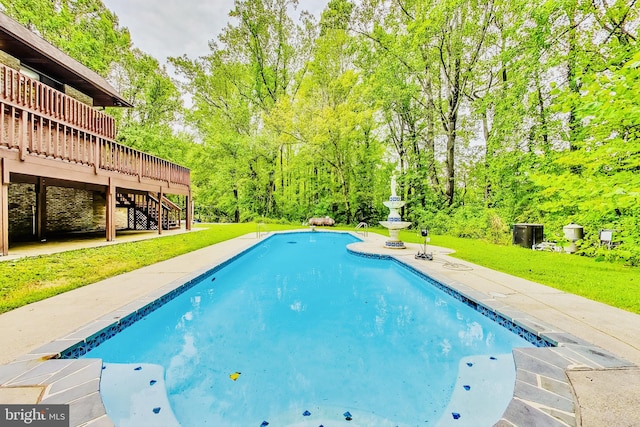 view of swimming pool featuring a wooden deck and a yard