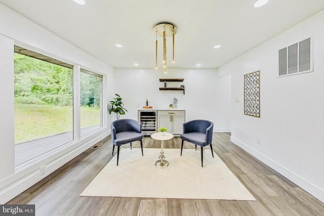 living area with wine cooler and light hardwood / wood-style floors