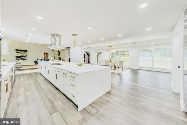 kitchen featuring a center island with sink, light hardwood / wood-style flooring, and white cabinetry