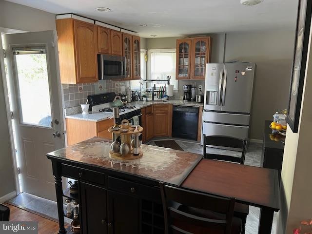 kitchen featuring decorative backsplash, light hardwood / wood-style flooring, stainless steel appliances, and light stone counters