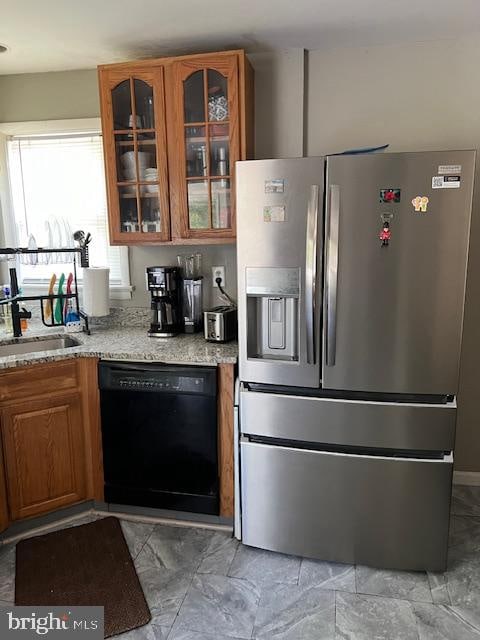 kitchen featuring stainless steel refrigerator with ice dispenser, light stone counters, dishwasher, and sink