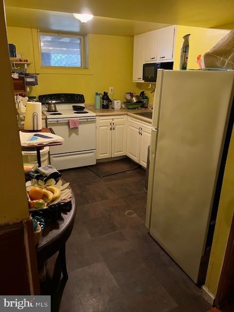 kitchen with white electric stove, stainless steel fridge, and white cabinets