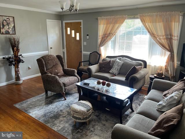 living room featuring ornamental molding, a notable chandelier, and dark wood-type flooring