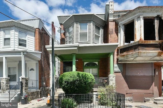 view of front of house with brick siding, a porch, and fence