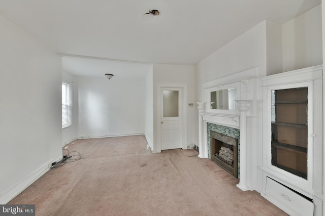 unfurnished living room featuring baseboards, a fireplace, and light colored carpet