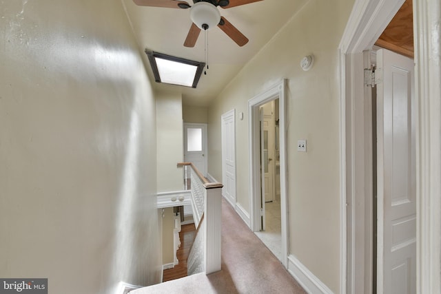 hall featuring baseboards, light colored carpet, and an upstairs landing