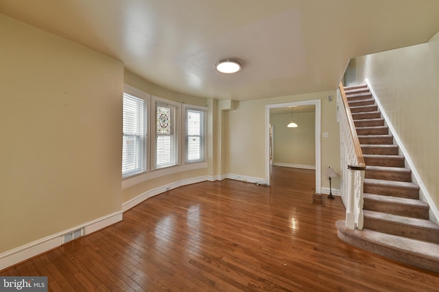 interior space featuring stairs, visible vents, baseboards, and wood finished floors