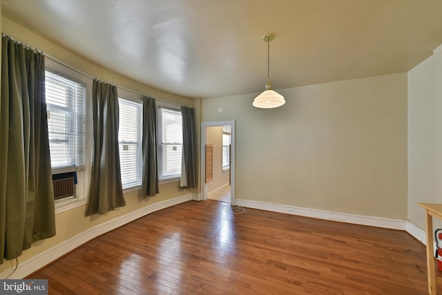 empty room with baseboards, wood finished floors, and a healthy amount of sunlight