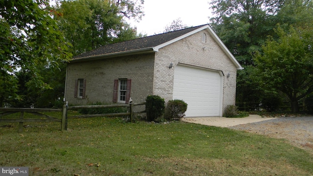 view of side of property featuring a garage, brick siding, an outdoor structure, fence, and a lawn