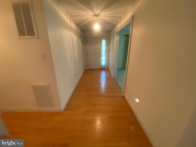 hall with visible vents, baseboards, and wood finished floors