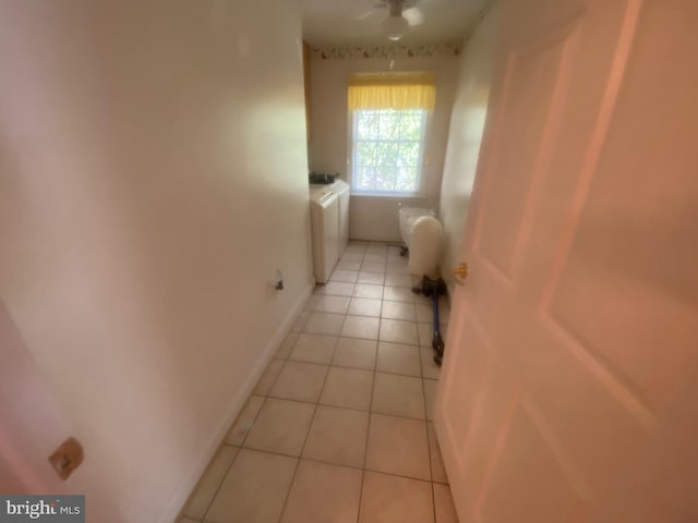 corridor featuring light tile patterned floors, baseboards, and washer / dryer