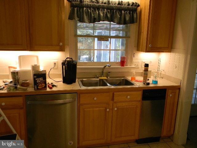 kitchen featuring dishwasher, sink, light tile patterned floors, and decorative backsplash