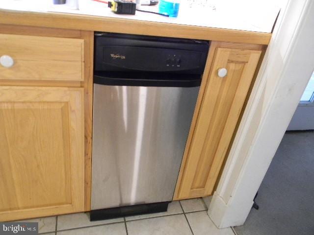 room details featuring light brown cabinetry, stainless steel dishwasher, and light tile patterned flooring