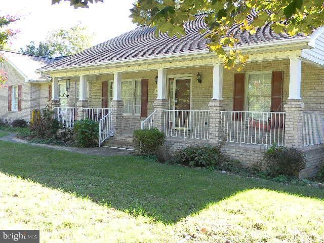 view of front of house with a front yard, a porch, and brick siding