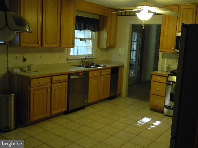 kitchen with brown cabinets, light countertops, a sink, and black appliances