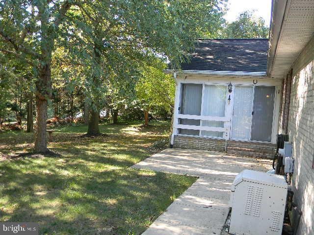 exterior space with a shingled roof and a lawn