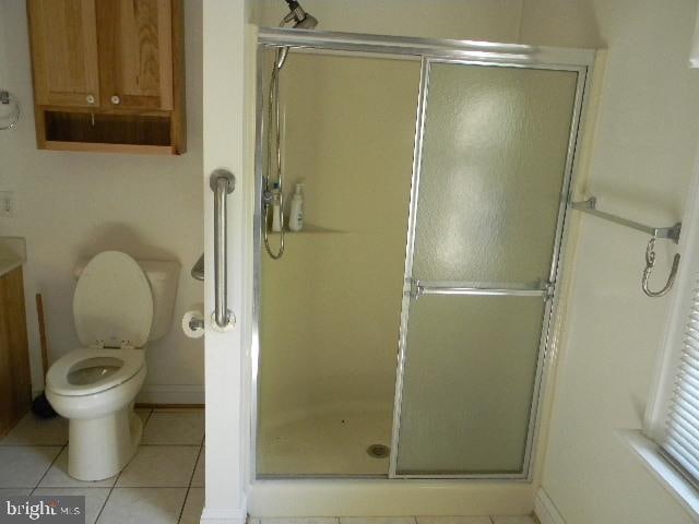 bathroom with a shower with door, vanity, toilet, and tile patterned flooring