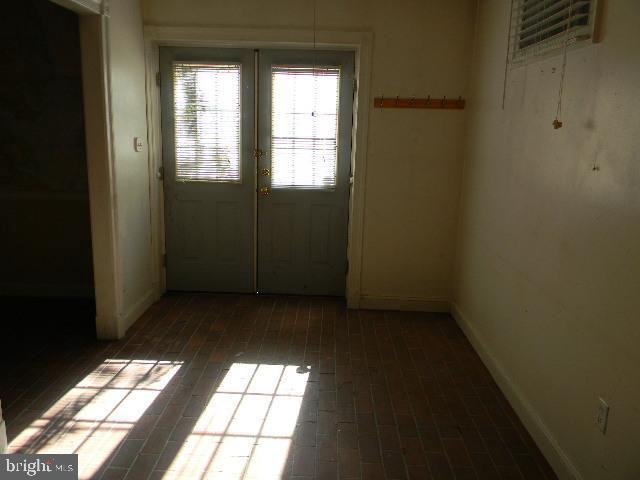 entryway with brick floor, baseboards, and french doors