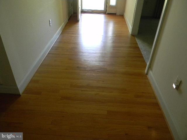 hallway with light wood finished floors and baseboards