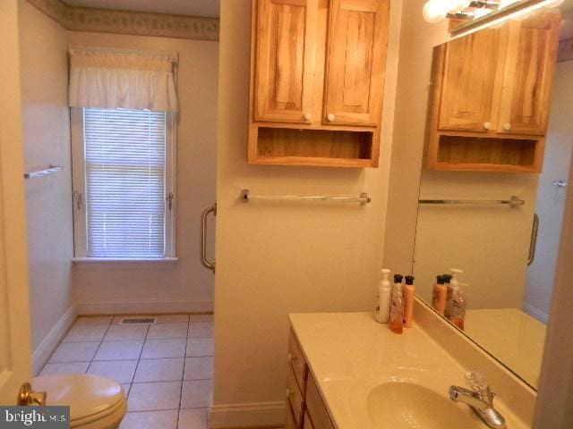 bathroom with tile patterned flooring, toilet, vanity, visible vents, and baseboards