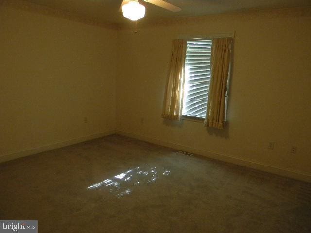 empty room with ceiling fan, visible vents, and baseboards