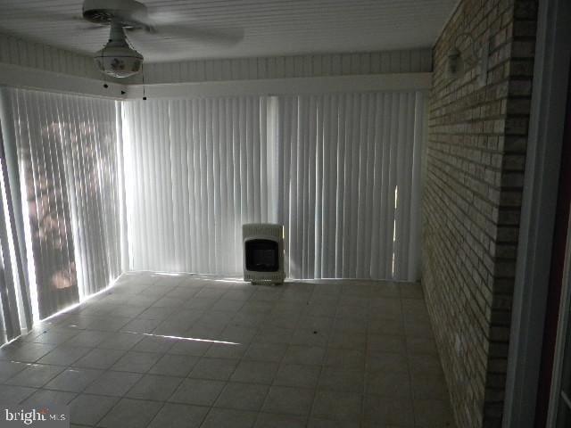 unfurnished sunroom with a ceiling fan and heating unit