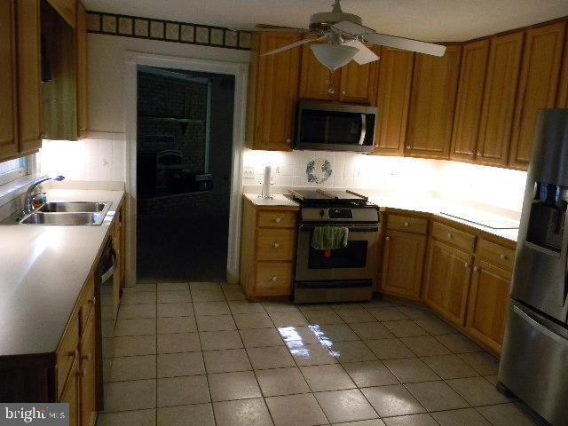 kitchen with a sink, stainless steel appliances, tasteful backsplash, and light countertops