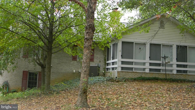 view of side of home featuring a sunroom, a chimney, and brick siding