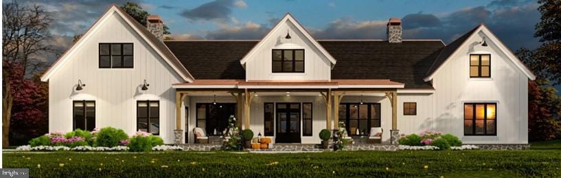 rear view of property featuring covered porch, a lawn, and a chimney