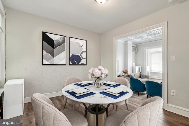 dining area featuring an AC wall unit and dark wood-type flooring