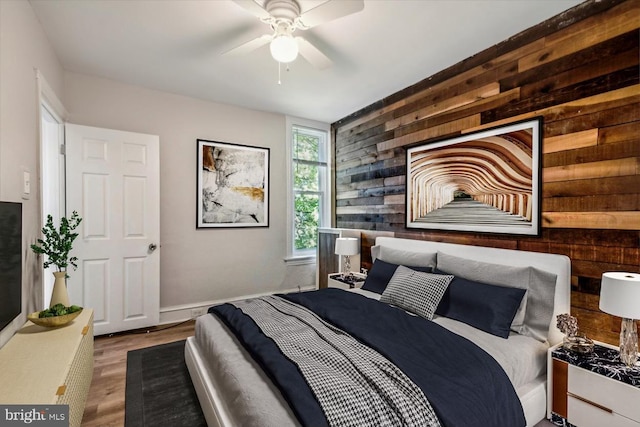 bedroom with ceiling fan, hardwood / wood-style flooring, and wooden walls