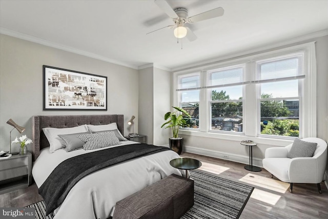 bedroom featuring multiple windows, ornamental molding, wood-type flooring, and ceiling fan