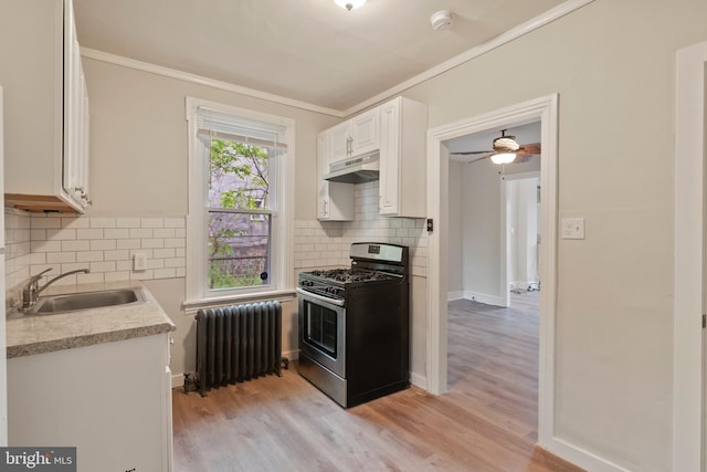 kitchen featuring radiator, sink, light wood-type flooring, stainless steel range with gas cooktop, and white cabinetry