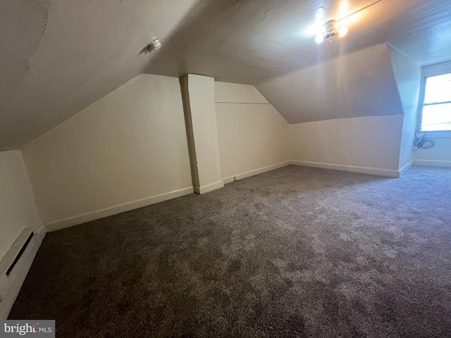 bonus room featuring baseboard heating, vaulted ceiling, and dark colored carpet