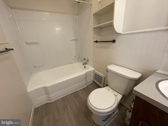 full bathroom with toilet, wood-type flooring, vanity, shower / washtub combination, and tile walls