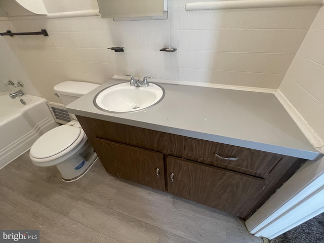 full bathroom featuring shower with separate bathtub, wood-type flooring, tile walls, toilet, and vanity