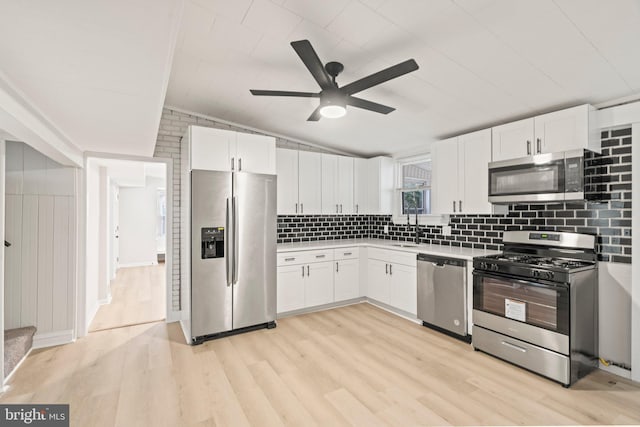 kitchen featuring decorative backsplash, light wood-type flooring, stainless steel appliances, and white cabinetry