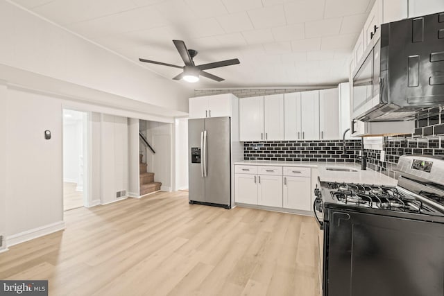 kitchen with white cabinets, light hardwood / wood-style flooring, stainless steel appliances, and backsplash