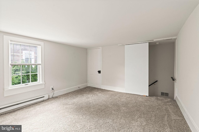 carpeted spare room with a baseboard heating unit