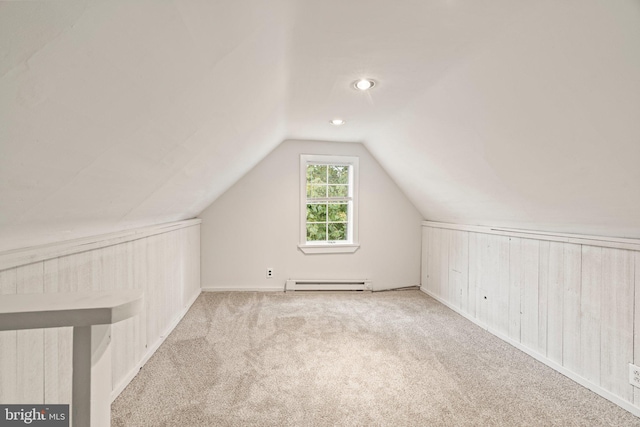 additional living space featuring light carpet, vaulted ceiling, a baseboard heating unit, and wood walls