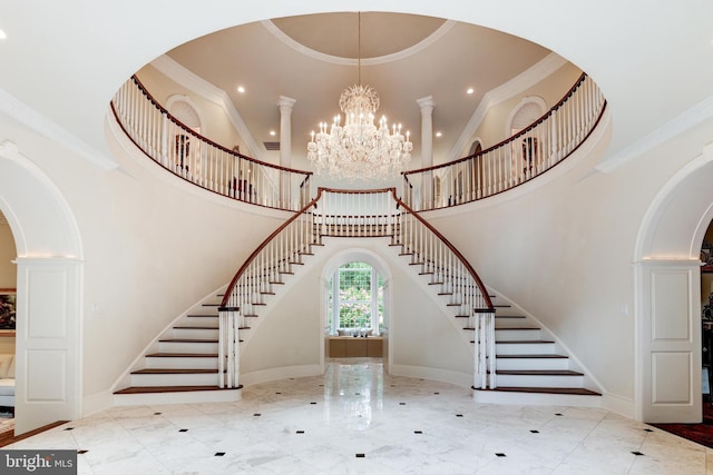 stairs with ornamental molding, a towering ceiling, and a chandelier