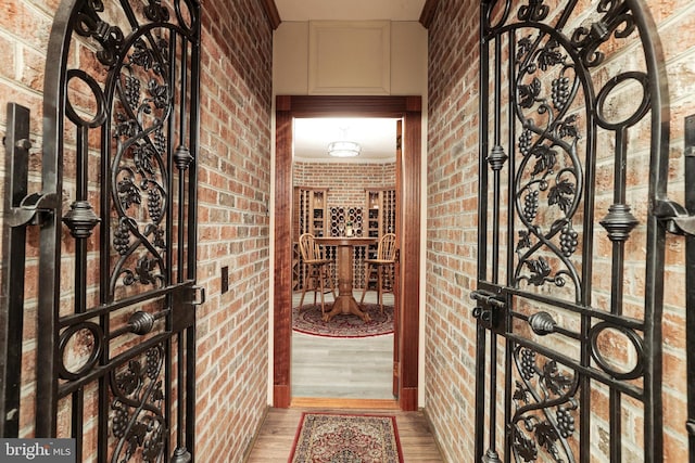 wine area featuring ornamental molding, wood-type flooring, and brick wall