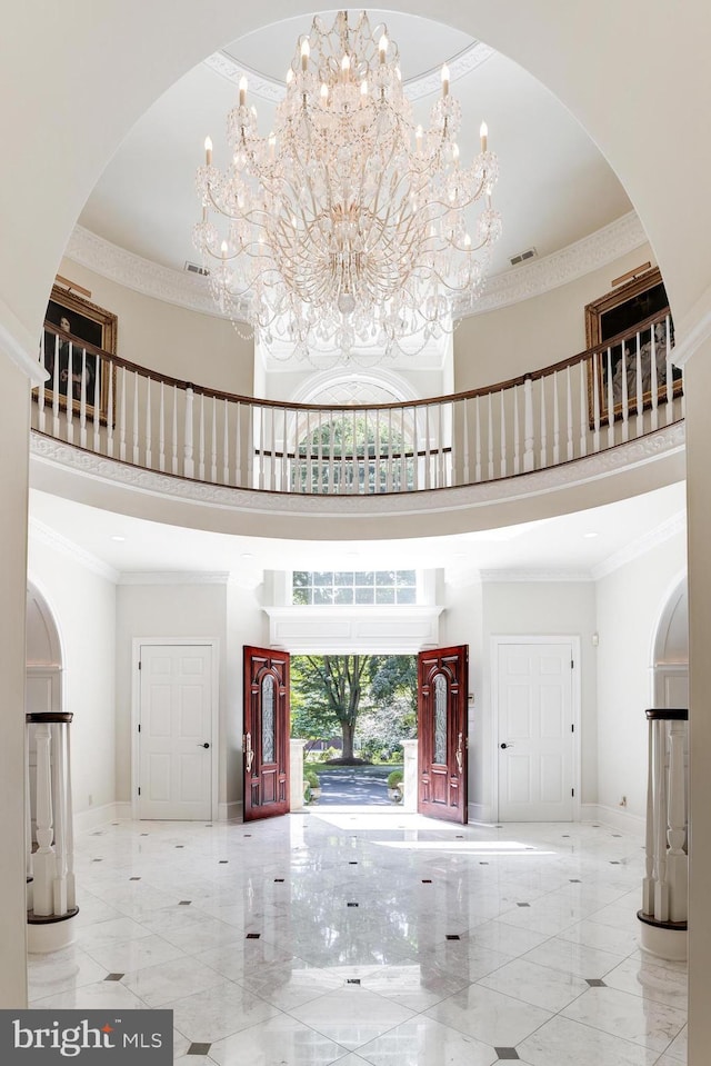 entrance foyer featuring a high ceiling, ornamental molding, and a notable chandelier